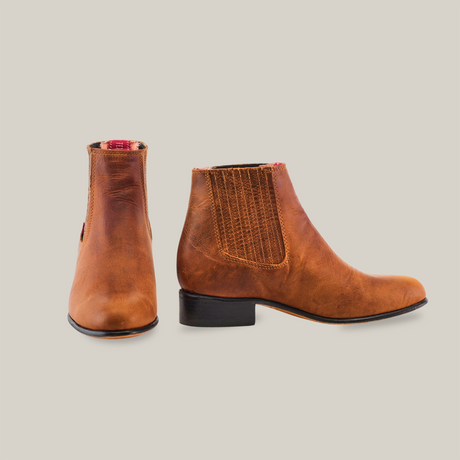 The Avejentado Honey - Round Toe boots, crafted from brown leather with a western style, are displayed on a white background. The left boot is angled forward while the right is shown in profile, showcasing the side elastic panels and low black heel.