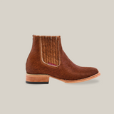 The Cowhide Hair Camel Square Toe ankle boot has a textured cowhide hair upper, side elastic panel, angled wooden heel, and smooth rounded toe. Its light sole contrasts with the dark exterior, offering a striking Western look against a white background.