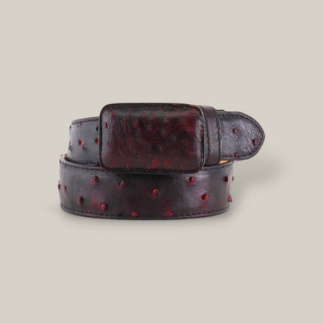 The Exotic Full Quilt Ostrich - Black Cherry Belt, with a luxurious ostrich texture featuring small round bumps and a rectangular buckle, is elegantly displayed coiled on a plain, light gray background.