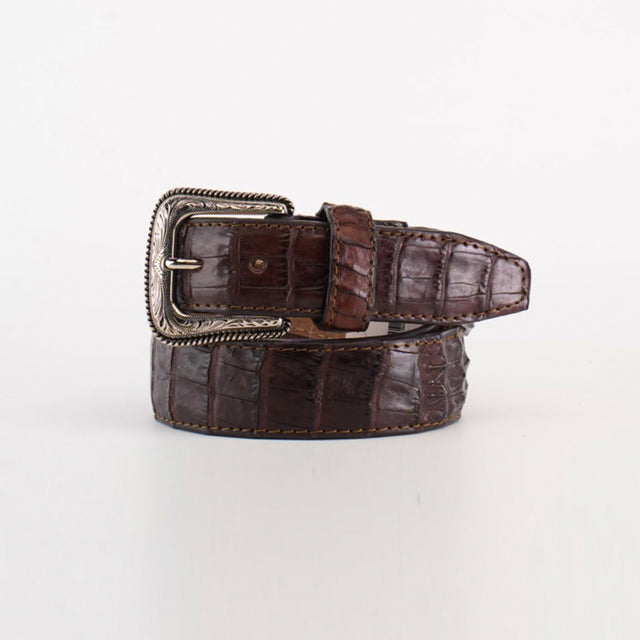 The Exotic Full Quilt Caiman - Texas Buckle - Brown Belt, with its luxurious crocodile leather and silver decorative buckle, exudes Western elegance. Its textured pattern enhances its refined appeal, coiled neatly on a plain white background.