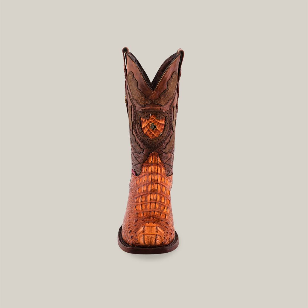 Front view of the Exotic American Alligator Head - Cogñac - Square Toe boot, crafted from alligator leather. Displayed against a plain backdrop, it showcases intricate patterns, brown and orange tones, and detailed stitching on its shaft and vamp.