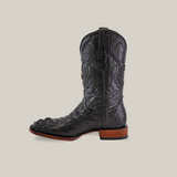 The Exotic American Alligator Head boot, in black, features a square toe design. Crafted from genuine alligator leather, it showcases a textured pattern and includes a wooden heel, displayed on a plain beige background.