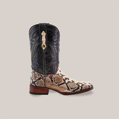 The Exotic Python - Natural - Rodeo Toe cowboy boot features a black leather upper and a Python-like lower. Its handcrafted with detailed shaft stitching, set on a wooden heel against a plain background.