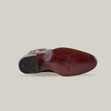 The image shows the underside of a Black Cherry Exotic Caiman Hornback dress shoe with a polished brown sole, decorative stitching, and logo near the heel. The front part is black with textured grip.