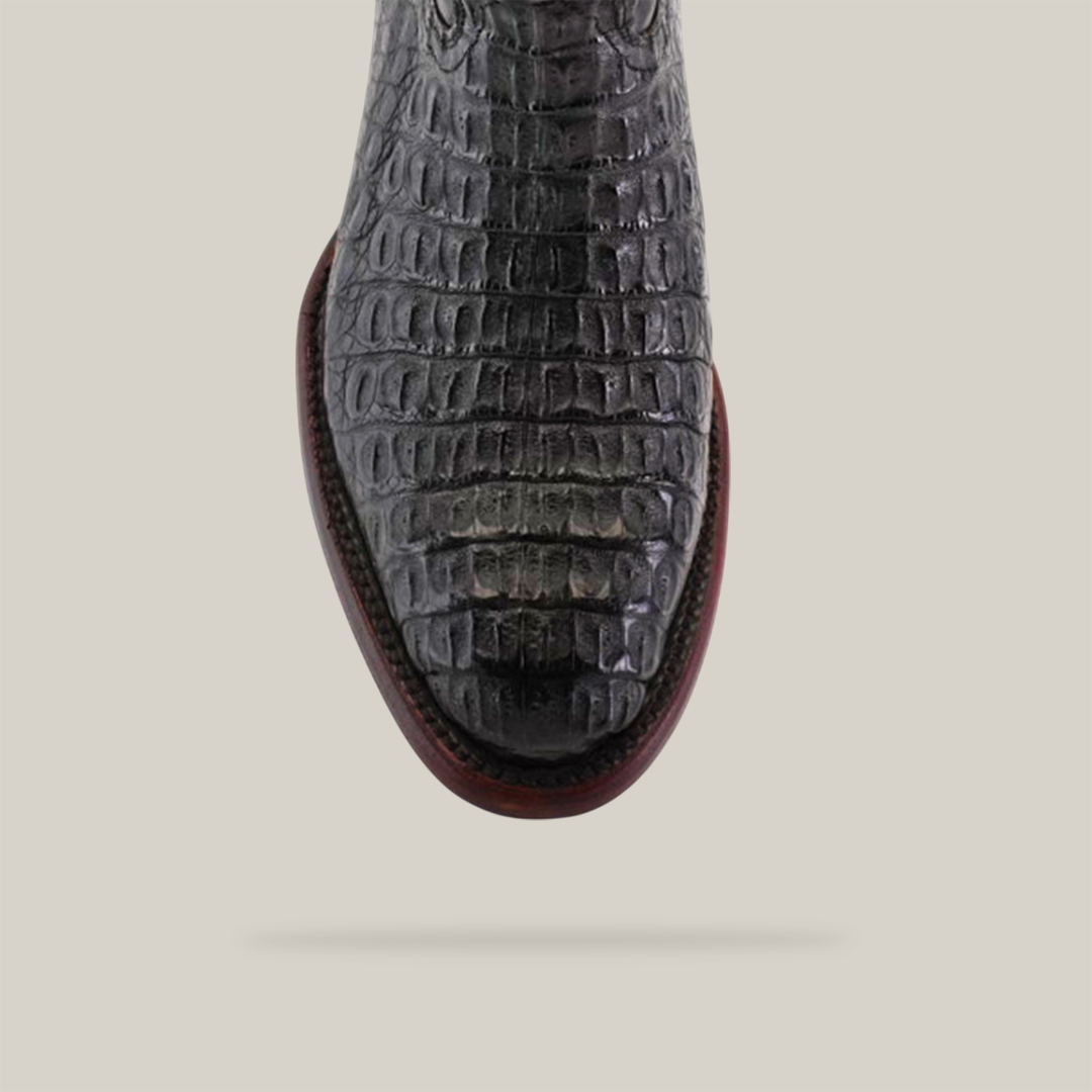 Close-up of Exotic Caiman Hornback - Black shoe with a crocodile pattern, viewed from the top, featuring a rounded toe and brown, slightly raised sole on a plain light background.