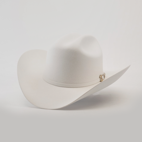 The 500X Superior White is a luxury Western cowboy hat with a wide brim and curved crown, made from top-quality belly beaver fur. It features a subtle band with a small gold emblem on a plain, light background.