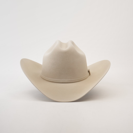 The 100X Independencia Belly, a beige cowboy hat made of premium full beaver fur, features a wide brim and a stylish crown crease, elegantly displayed on a plain white background.