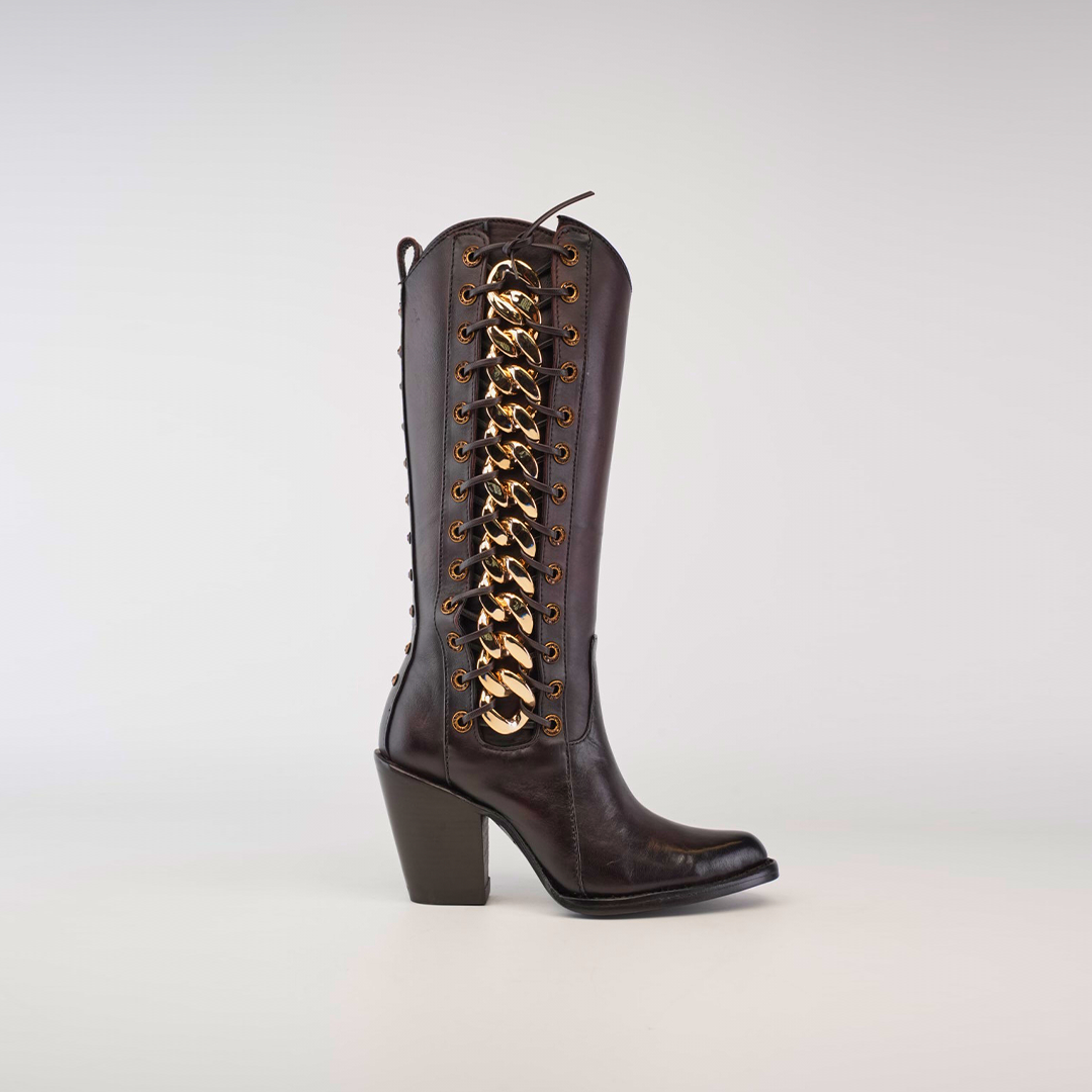 Introducing the Francia Rings Tall Shaft Chocolate, a luxury boot made from premium chocolate leather with a knee-high design. It features a chunky heel, elegant lace-up style, striking gold chain detailing on the side, and a convenient pull tab at the top.