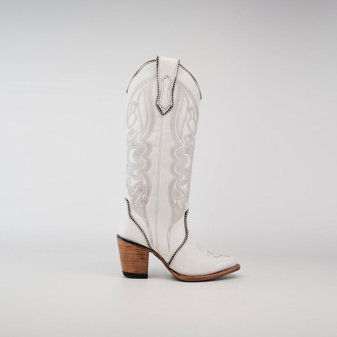 The Linda Studs Tall Shaft Frost White - J Toe cowboy boot features intricate artisanal craftsmanship, a tall shaft, and a brown stacked heel. Part of the Platinum Collection, its crafted from premium leather for timeless elegance against a plain gray background.