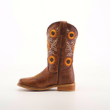 The Sunflowers Tabaco - Square Toe cowboy boot boasts exquisite sunflower and leaf embroidery on the shaft. It features a wooden heel and stitched square toe, all against a plain white background, accentuating its premium leather finish and superior craftsmanship.