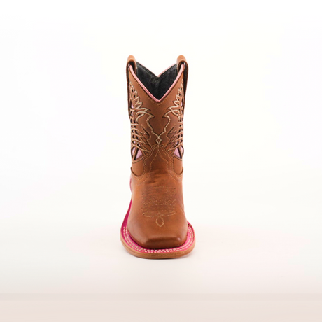 The Dube Tan Pink Outline features a front view of a single brown cowboy boot, expertly crafted with intricate stitching on the shaft. Made from premium handcrafted leather, it has a square toe and red accents on the sole against a plain white background.