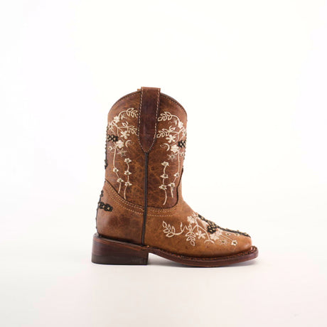 The Margacruz Studs Orix - Square Toe, a brown cowboy boot, is handcrafted from premium leather with delicate white floral embroidery on the side. Displayed against a plain white background, it highlights its low heel and sturdy leather sole.