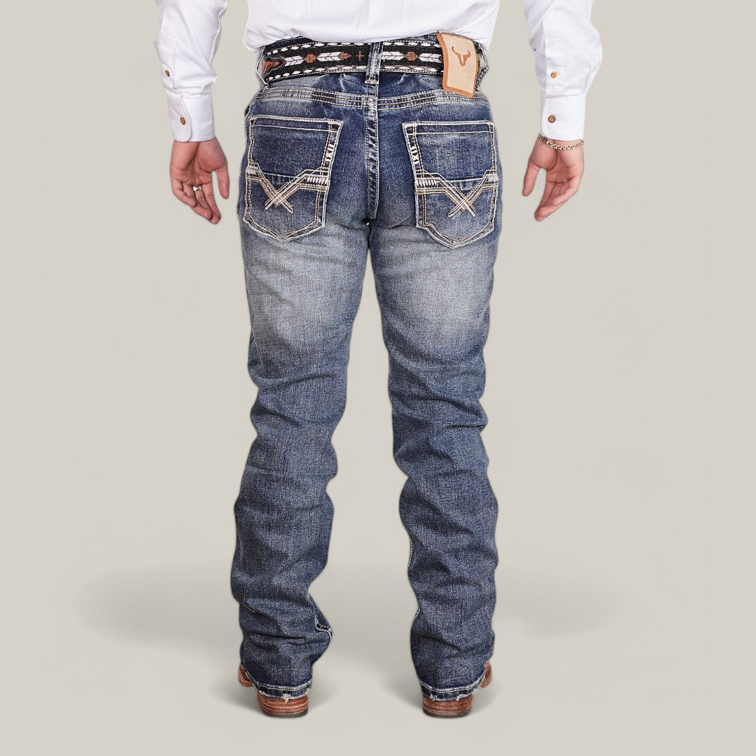 A person in a white shirt and Western Blue Straight Fit Embroidered Jeans - W436, featuring decorative stitching on the back pockets and a detailed belt. These slightly faded jeans offer a flattering fit, paired with brown shoes against a plain light background.