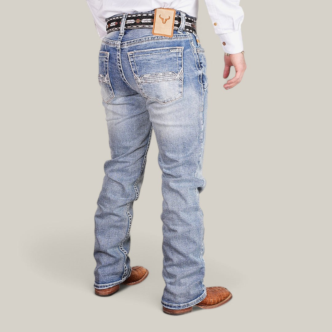 A person in light blue distressed Western Blue Straight Fit Embroidered Jeans - W430, a white shirt, black and white belt, and brown shoes stands facing away with legs slightly apart. A tan patch with a bull logo is visible on the waistband.