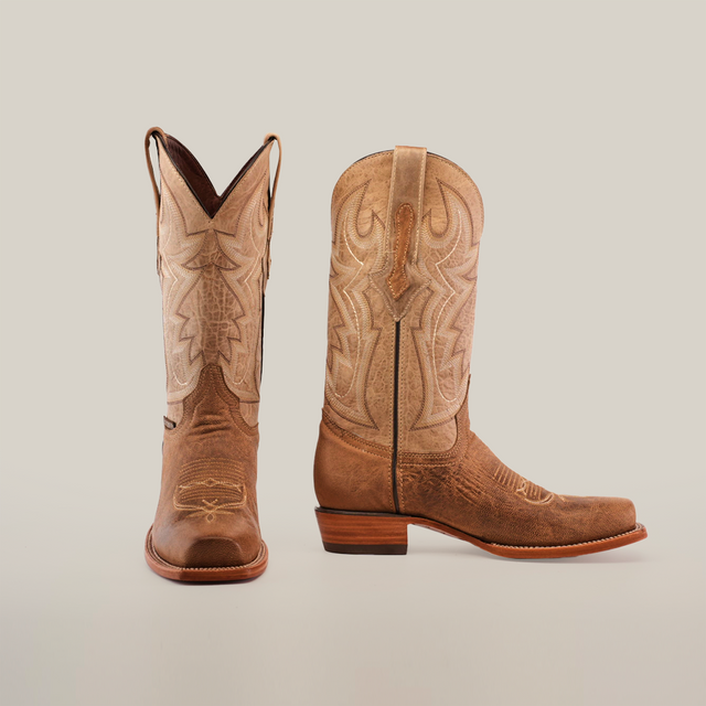 A pair of Sierra Fawn - Wide Cutter Toe cowboy boots made from premium cowhide leather, featuring intricate stitching and pull straps, is displayed on a white background; one boot faces forward while the other shows the side profile with heel and design details.