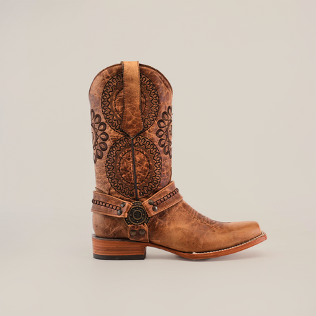 The Siberia Fawn - Biker Toe is a single brown cowboy boot made from premium cowhide, featuring intricate circular stitching on the shaft, an ankle strap with a decorative buckle, and a sturdy wooden heel set against a plain white background.