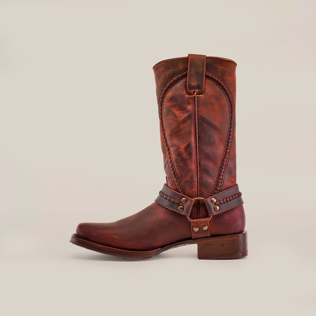 The Azkar Moka - Slip Resistant Sole - Biker Toe boot, crafted from brown leather with decorative stitching and a strap, stands upright against a white background. This handcrafted boot features a slightly worn look, low heel, and slip-resistant sole for added stability.