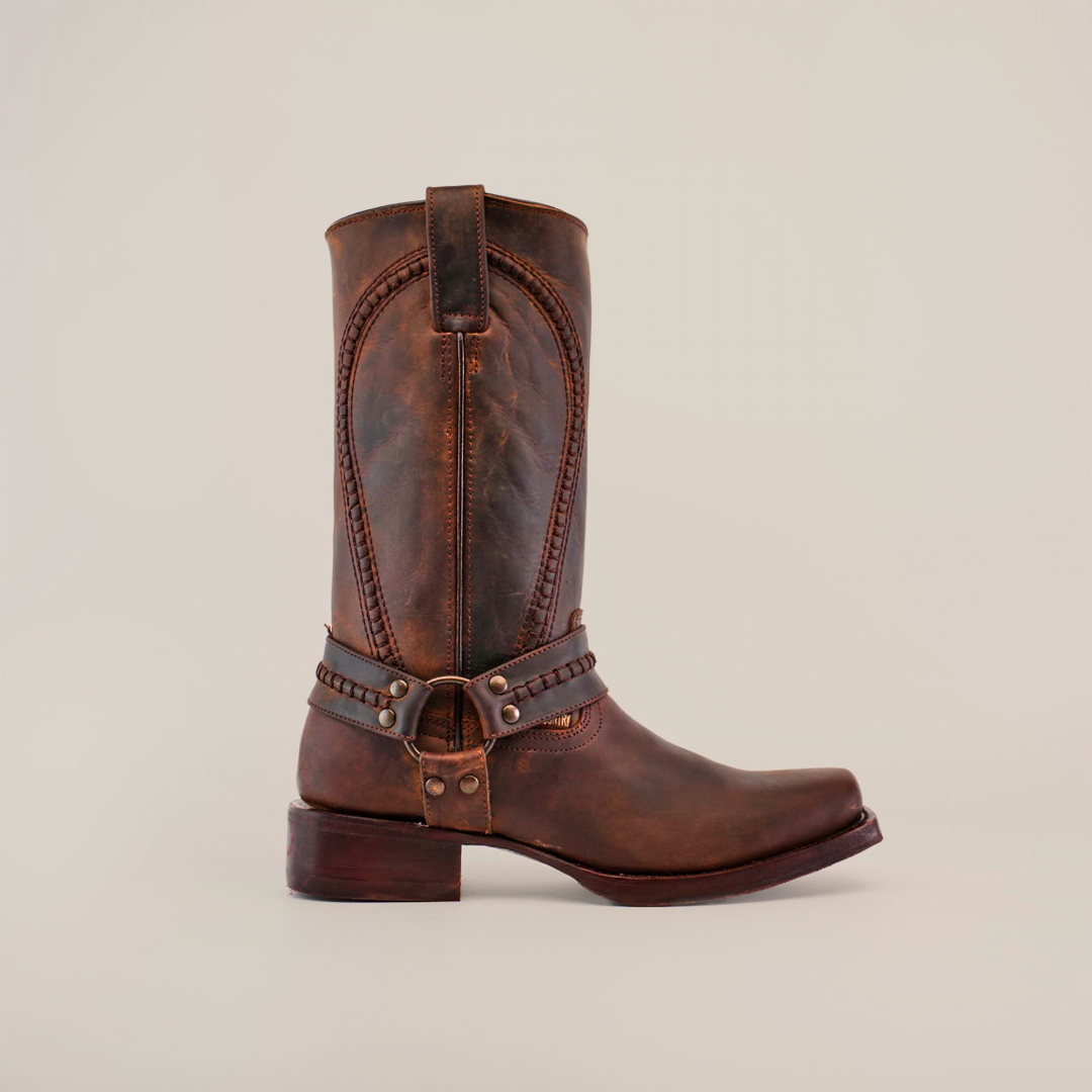 Introducing the Azkar Tan boot: a single handcrafted brown leather piece with decorative stitching and metal accents, displayed on a white background. Made from premium cowhide, it features a biker toe, low heel, and slip-resistant sole for stability.