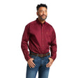 A man confidently stands with hands on hips in a Solid Twill Classic Fit Shirt Burgundy - 10012635, paired with blue jeans and a brown belt. The shirt features a chest pocket logo, while he smiles slightly against the plain white backdrop.