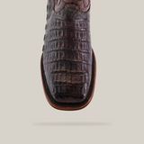 Close-up of the Exotic Caiman Belly Tail boot from the Diamond Collection in Tabaco brown with a square toe design, set against a plain beige background.