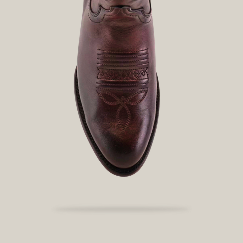A close-up of the Roper Toe on the Platinum Brown Western boot highlights detailed stitching, featuring a floral design, set against a light background.