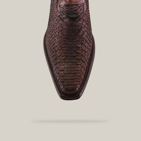 A top view of a single Exotic Python - 4G - Matte Brown shoe from the Platinum collection, showcasing its Versy toe and Goodyear welt sole. The brown leather features a snakeskin texture against a plain beige background, with its shadow subtly cast below.