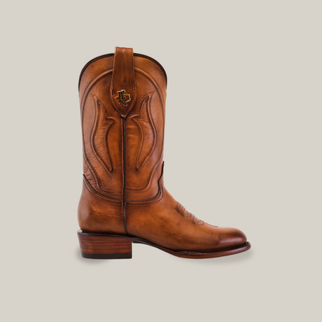 The Western - Platinum - Honey - Roper Toe is a single brown cowboy boot with classic style, detailed stitching, a rounded Roper toe, and a low wooden heel. It features a pull tab with a small metal emblem against a plain white background.