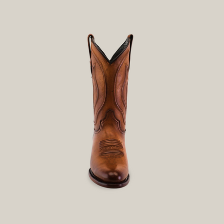 The Western - Platinum - Honey - Roper Toe cowboy boot, with its decorative stitching and rich leather texture, stands upright against a white background. It embodies classic Western style with its tall, pointed shape reminiscent of tradition.