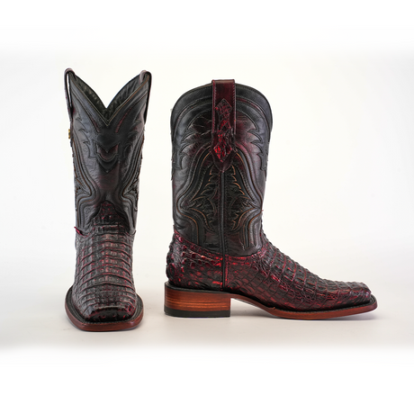 The Exotic Caiman Hornback boots in Black Cherry with a Rodeo Toe showcase one boot facing forward and the other to the side, highlighting their dark tones, intricate patterns, textures, wooden heel, and authentic caiman leather mix of smooth and scaly surfaces.