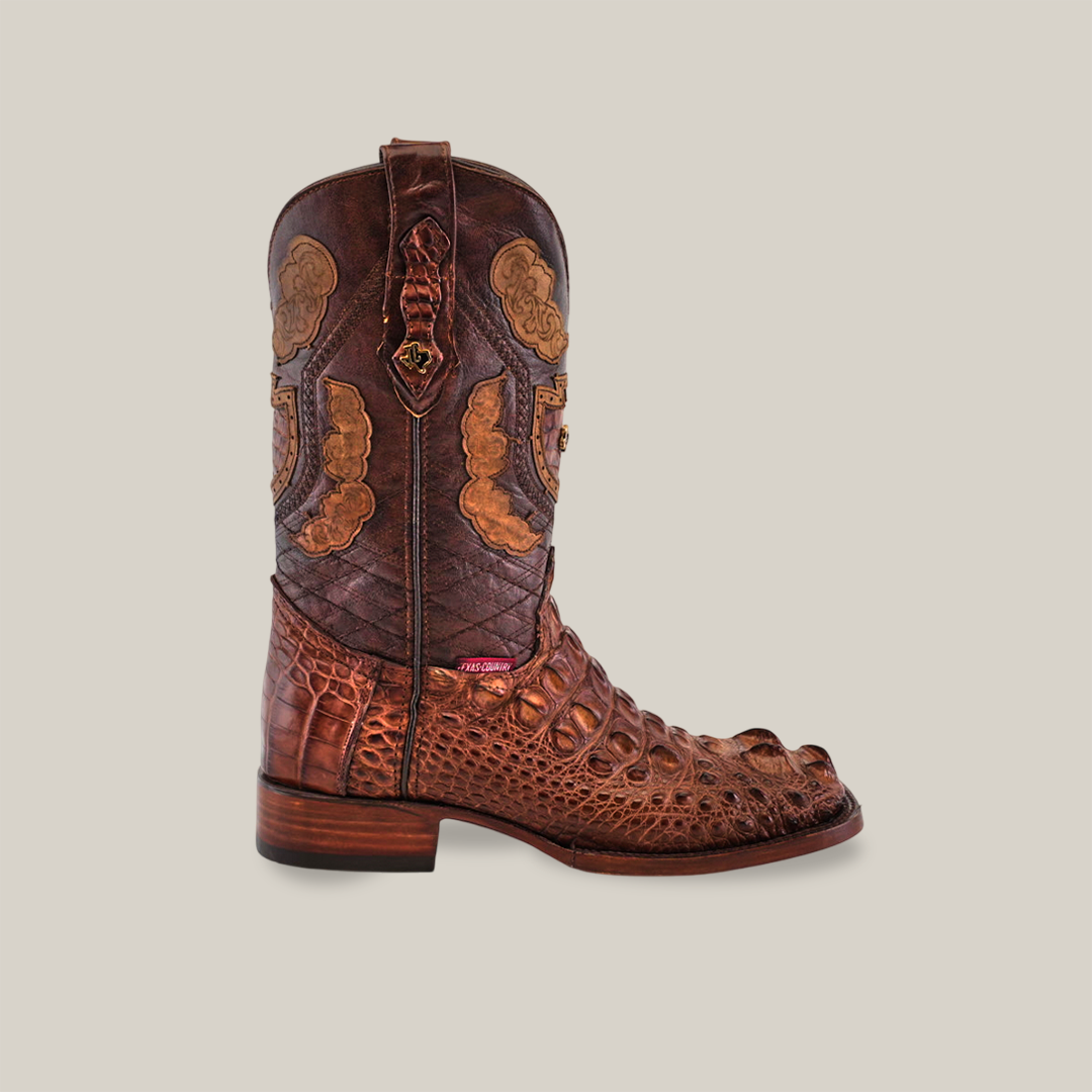 A single intricately designed cowboy boot features the Exotic American Alligator Head in brown, boasting a high shaft and mixed leather textures. Handmade with detailed patterns, it has a square toe and wooden heel, set against a neutral background.