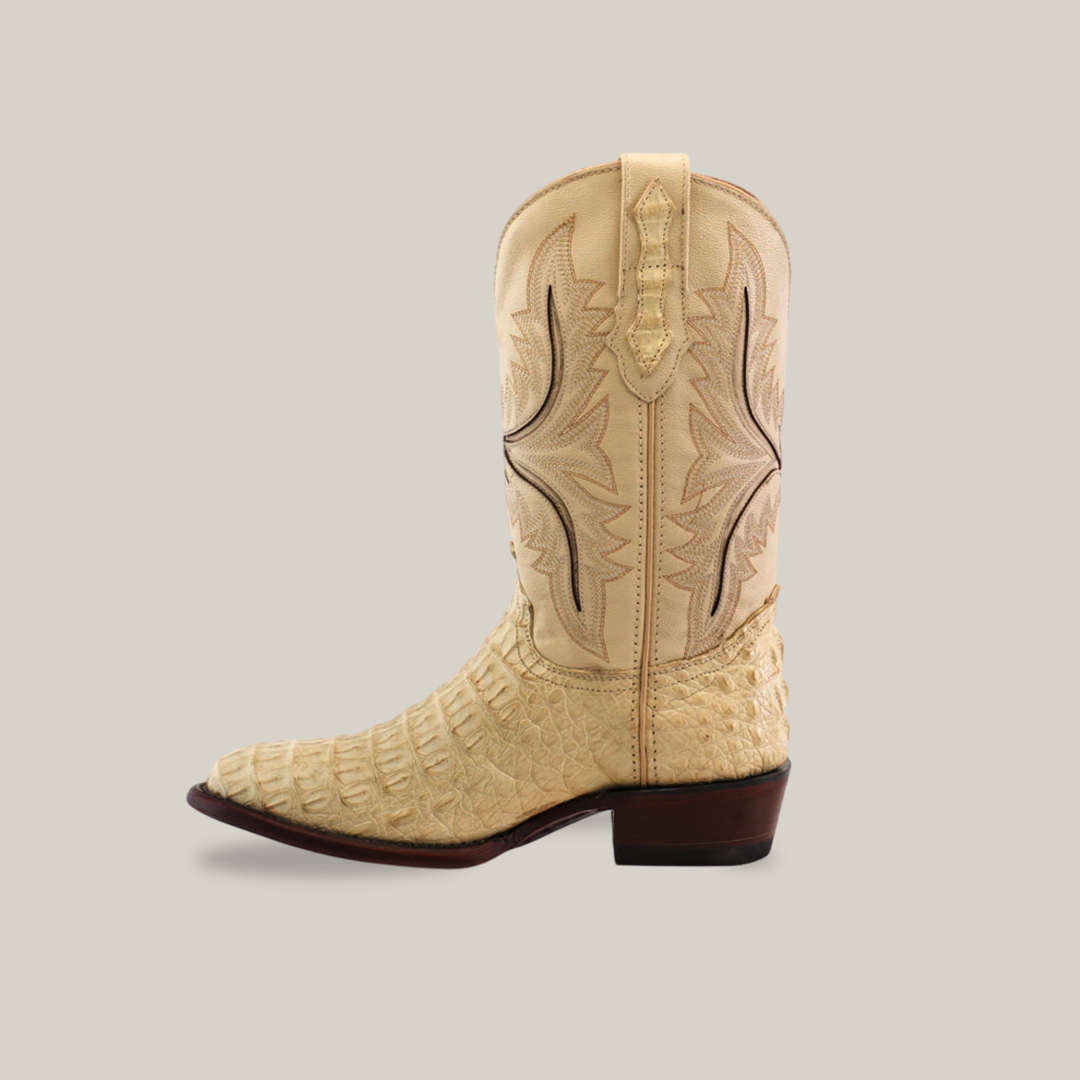 A single Exotic Caiman Hornback - Bone - Round Toe Western-style cowboy boot is crafted from authentic caiman leather with intricate stitching and a textured pattern. It features a high shaft and a brown heel, set against a light gray background.