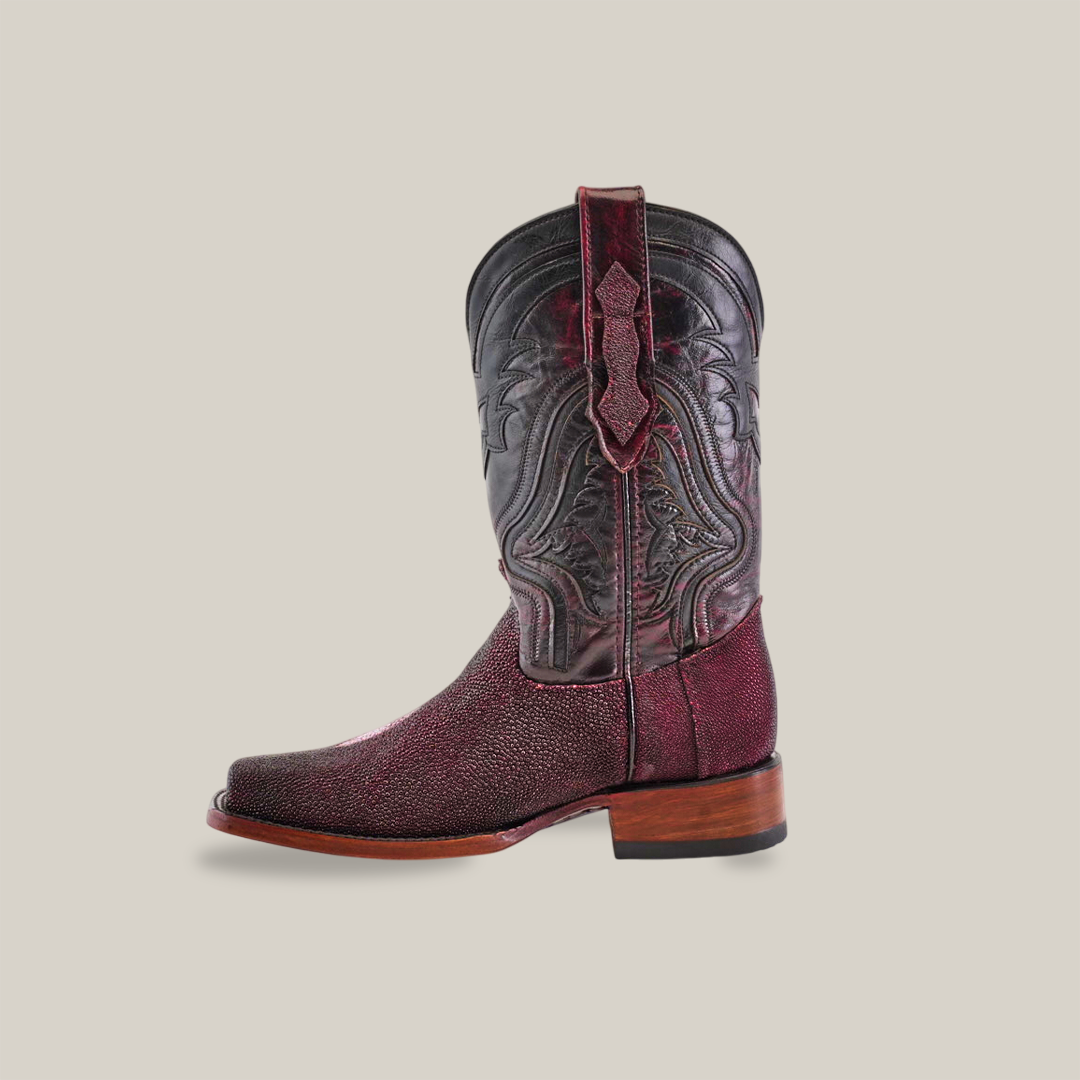 A single Exotic Stingray - Wine cowboy boot, crafted from luxurious stingray leather with intricate black stitching and a wooden heel, set against a plain beige background.