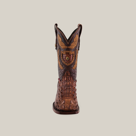 Front view of the Exotic American Alligator Head cowboy boot featuring intricate leather detailing, a square toe, rich brown color, decorative patterns with a crest design, all set against a plain beige background.