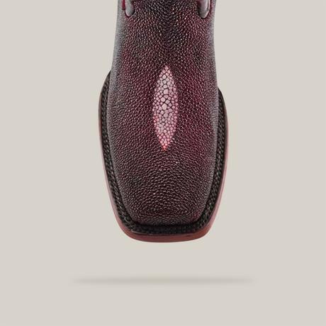 An overhead shot showcases the Exotic Stingray in Wine, crafted from luxurious stingray leather. This boot features a Rodeo toe with a striking light patch center. The textured surface stands out against the plain, neutral background.