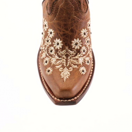 Top view of the Abril Studs Orix Snip Toe boot, showcasing intricate white floral embroidery on brown leather. The detailed stitching adds texture and contrast, while the childrens sole design is visible around the edges.