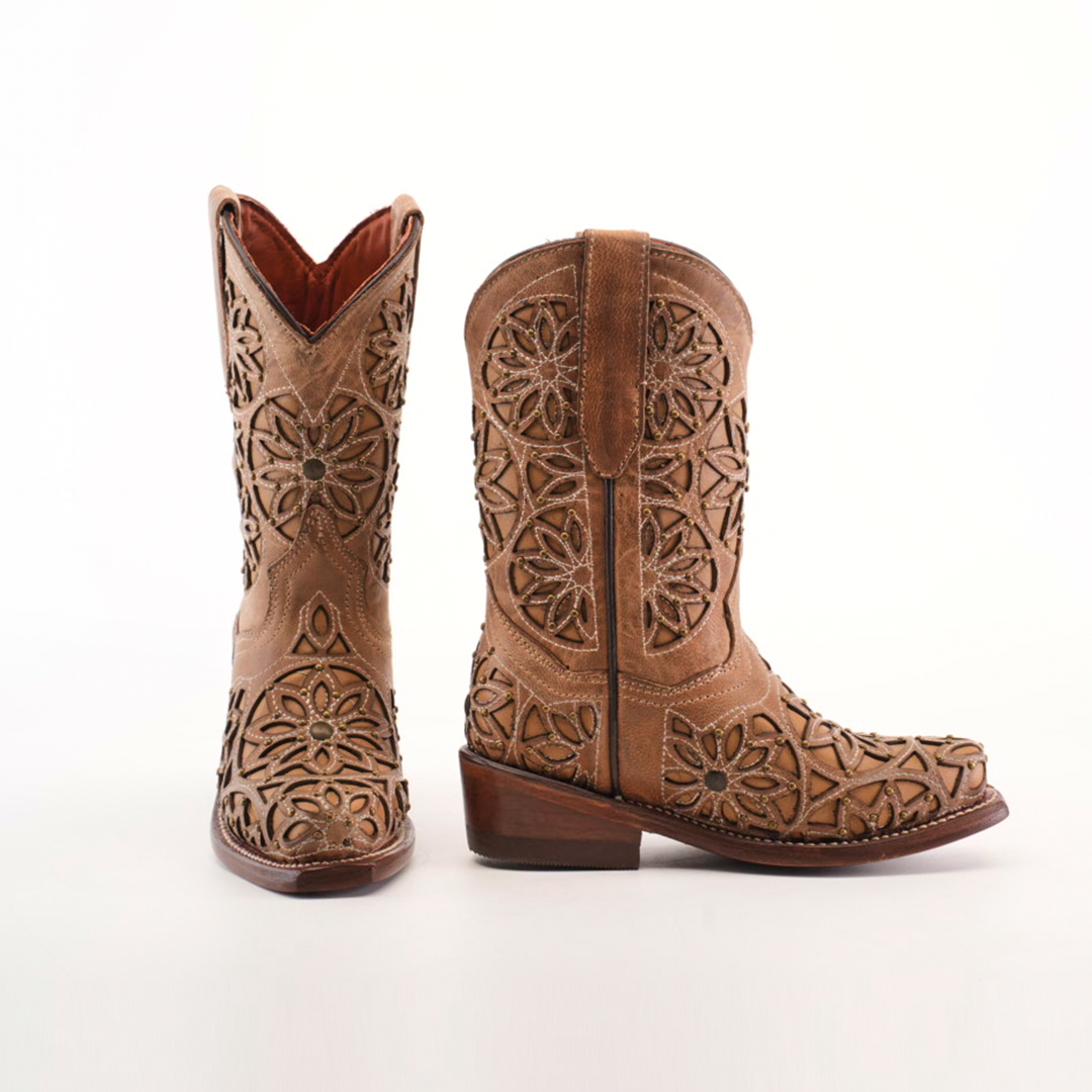 The Vitralli Studs Fawn Snip Toe boots feature intricate floral cutout designs on tan premium leather. One boot faces forward and the other is turned, highlighting the detailed craftsmanship and wooden heels.