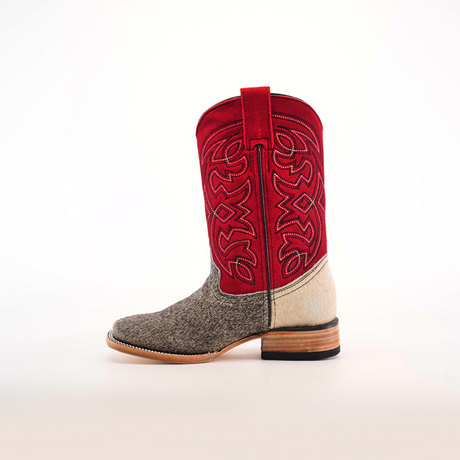 The Cowhide Hair Pinto Square Toe boot showcases a textured gray and brown hair-on-hide lower half with a vibrant red upper shaft adorned with intricate patterns. It features a square toe design and heel in natural wood tones, all set against a plain white background.