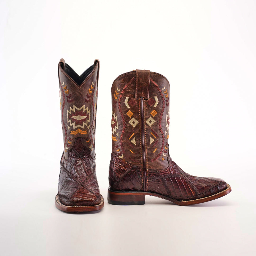 The Exotic American Alligator Patchwork Brown Square Toe boot is depicted on a white background, showcasing intricate geometric and arrow embroidery. It features a rugged texture and low heel, crafted from genuine alligator skin for an exotic appeal.