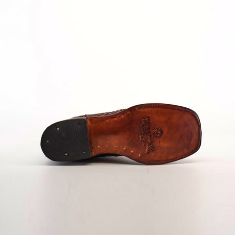 The image showcases the sole of an Exotic American Alligator Patchwork Brown Square Toe boot, made from premium brown leather with a wood-like texture and visible nails. A black rubber pad accents the heel, while an embossed logo is centered. The shoe rests elegantly on a plain white background.