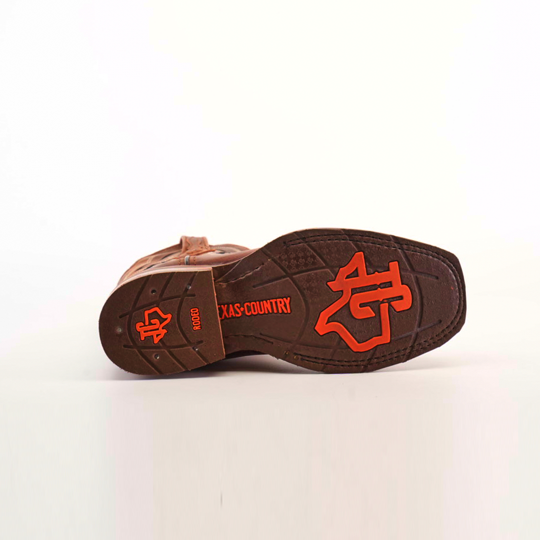 The image shows the slip-resistant sole of a Fresno Shedron Slip Resistant Sole Rodeo Toe cowboy boot, featuring red text and symbols. It highlights NGD, TEXAS COUNTRY, and a logo with a cowboy hat and Texas outline on a white background that accentuates each detail.