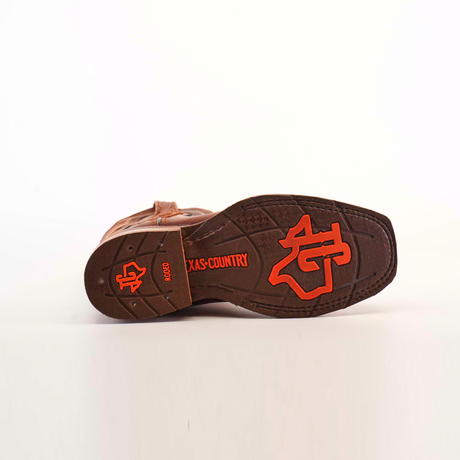 The image shows the slip-resistant sole of a Fresno Shedron Slip Resistant Sole Rodeo Toe cowboy boot, featuring red text and symbols. It highlights NGD, TEXAS COUNTRY, and a logo with a cowboy hat and Texas outline on a white background that accentuates each detail.