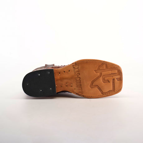 The Karoo Ostrich Print Chocolate Square Toe shoe boasts premium brown leather, a distinct logo, and a well-crafted sole with detailed tacks on the black heel against a white background, all highlighting its quality construction and design elegance.