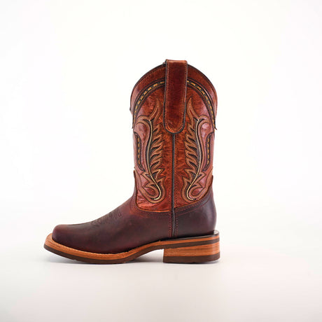 An Azkar Moka Slip Resistant Sole Rodeo Toe boot in brown leather, showcasing intricate stitching, is set against a plain white background. With a rounded toe and wooden heel, this stylish and functional boot is perfect for any occasion needing slip-resistant soles.