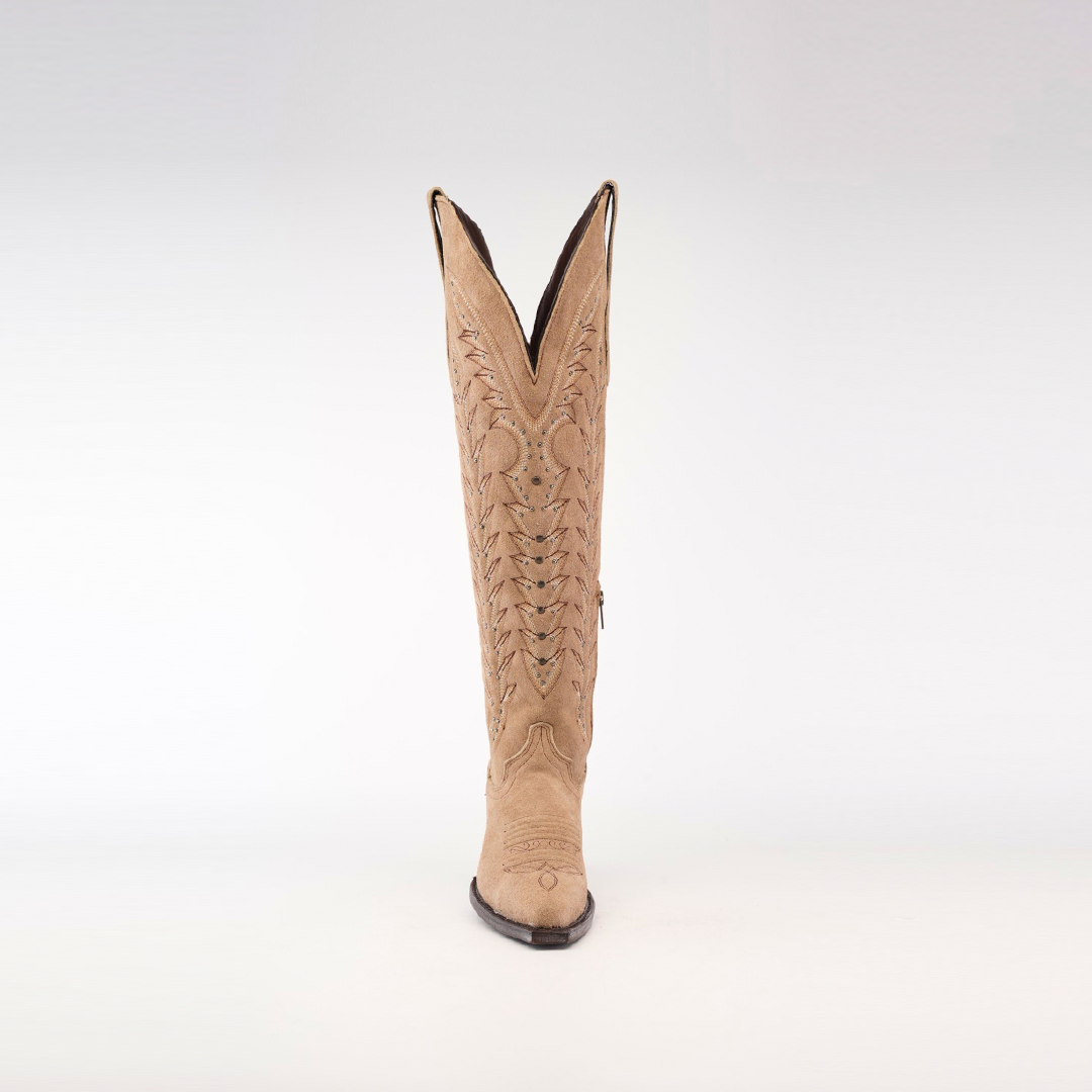 A single Madona Sand Suede boot is displayed upright on a white background. The tall shaft features intricate stitching, a snip toe, and a distinctive V-shaped top, all crafted from fine light tan suede.