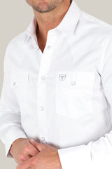 Man wearing a Men’s Single Pocket Logo Modern Fit Stretch Dress Shirt - White (CTL9259), stands with clasped hands. The shirt features snap buttons and one chest pocket. His head isnt fully visible in the image.