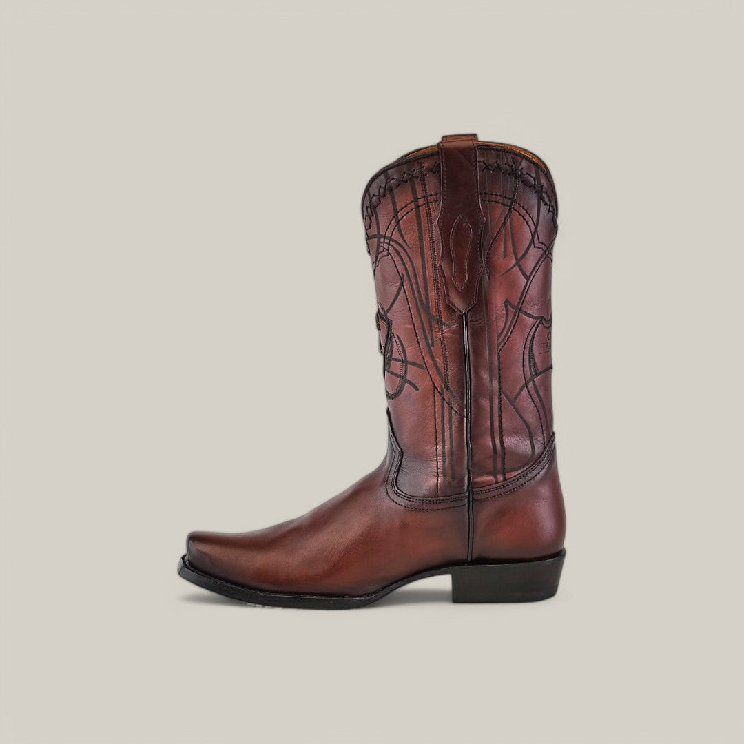 A brown leather cowboy boot, matching the Over Chestnut Laser & Embroidery style with its narrow square toe and low heel, stands against a plain background. Its high shaft and decorative stitching embody Cuadras classic Western aesthetic.