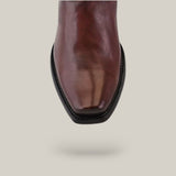 Close-up of an Over Chestnut Laser & Embroidery - Narrow Square Toe (CU347) boot in polished brown leather with black stitching, set against a light gray background.