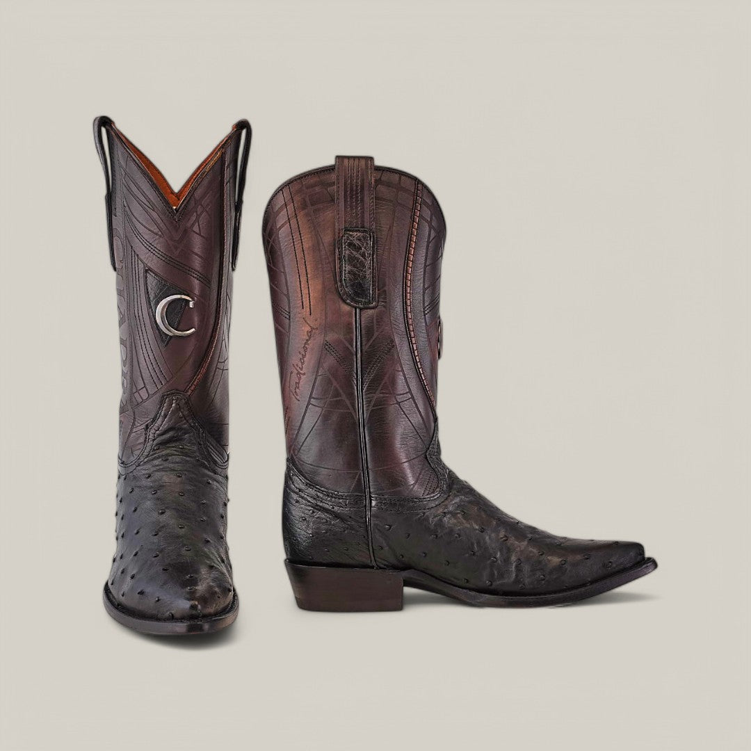 A pair of Cuadra Black Ostrich Laser & Embroidery boots displays intricate stitching and a shiny texture. The left boot features a decorative emblem on the shaft. These stylish snip toe CU807 boots with a medium heel are set against a plain, light background.