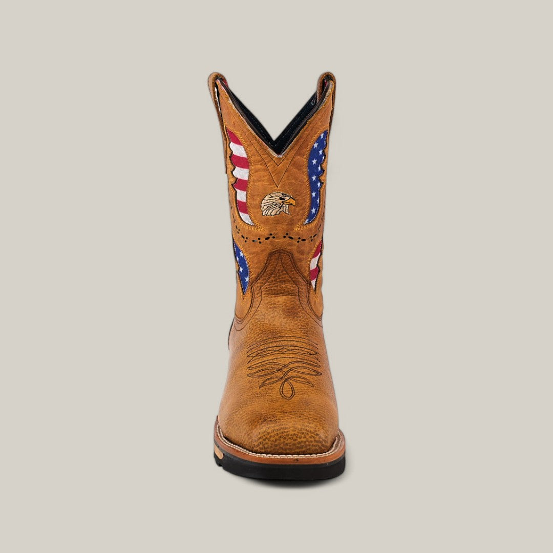 The Taurus Honey Composite Toe - E6189 is a tan cowboy boot featuring an eagle and American flag design on the shaft, with Texas country style. It has curved stitching on the toe, a dark sole for durability, perfect for hardworking days, and stands upright against a plain background.