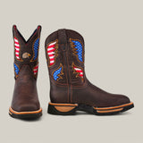 The Taurus Moka Composite Toe - E6189 boots are dark brown cowboy boots with American flag patterns, wing designs, and an eagle emblem. They feature a thick sole and contrasting stitching, ensuring durability for any adventure.